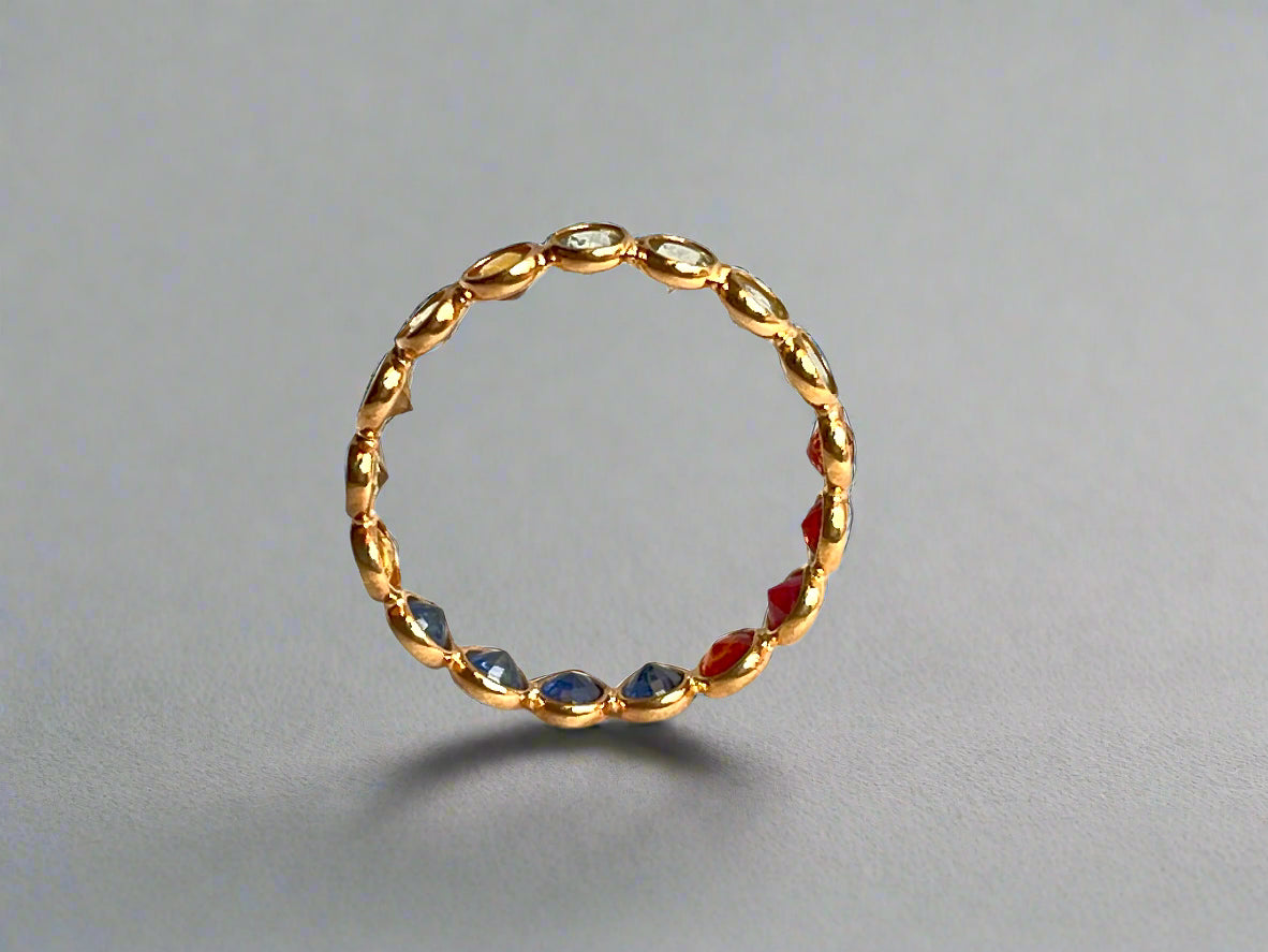 Gold ring with embedded red and blue stones on a gray background