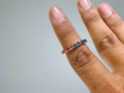 Multicolored gemstone ring on a finger against a white background