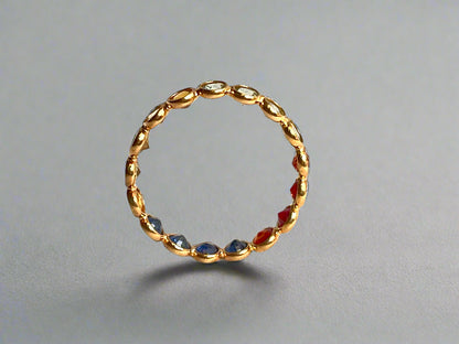 Gold ring with embedded red and blue stones on a gray background