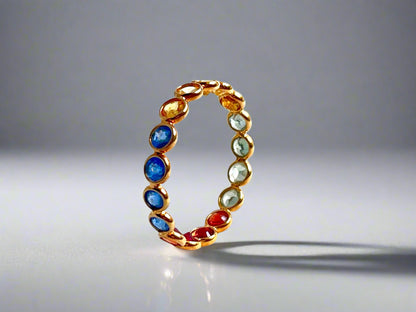 Gold ring with multicolored gemstones on a gray background